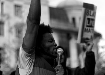man in white t-shirt raising his right hand