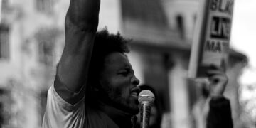 man in white t-shirt raising his right hand